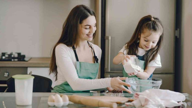 A girl helps her mother in the kitchen, showing the authentic joy of helping in children.