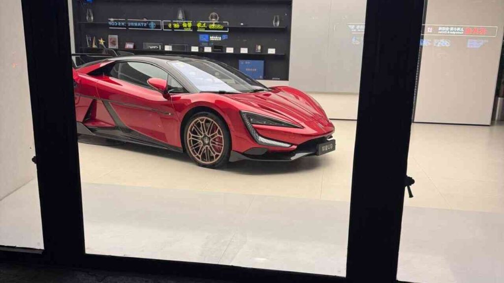 A red electric Yangwang U9 sports car in a showroom in China, a symbol of the modernity described in Michał Dziuda’s “Notes from China” series.