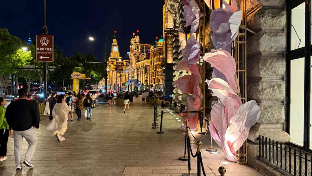 A nighttime street in Shanghai during a journey to China, with illuminated buildings and pedestrians against the backdrop of the city center.