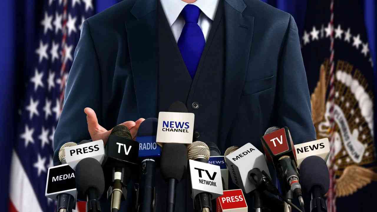 A man in a suit answers questions into microphones at a press conference.