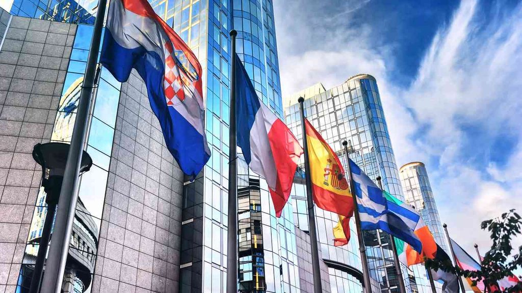 Flags of member states in front of the headquarters of European institutions. EU enlargement requires the unanimous consent of all members, which means that even EU candidate countries that meet the formal conditions may wait years for the accession process to conclude.