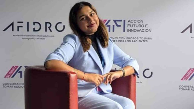 Gitanjali Rao sitting in an armchair, with a white branded backdrop in the background.