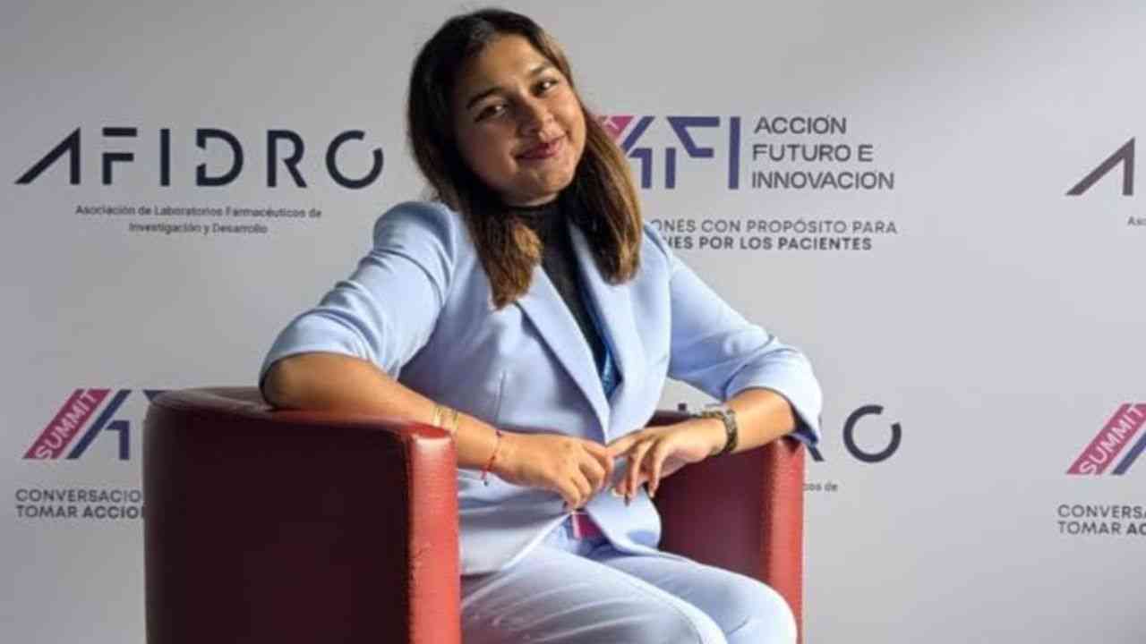 Gitanjali Rao sitting in an armchair, with a white branded backdrop in the background.