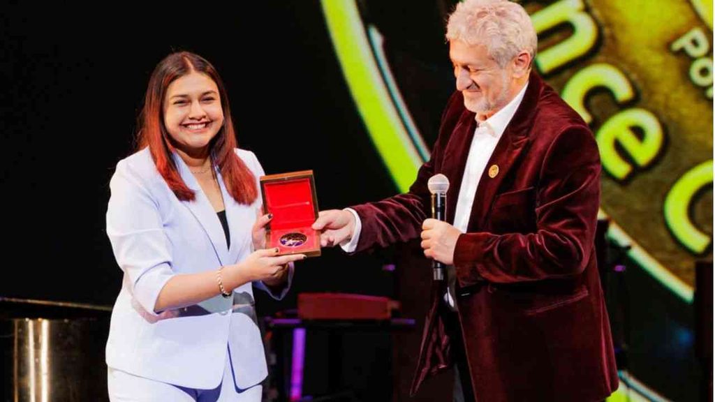 Gitanjali Rao receives an award on stage from an older man for young researchers’ inventions.