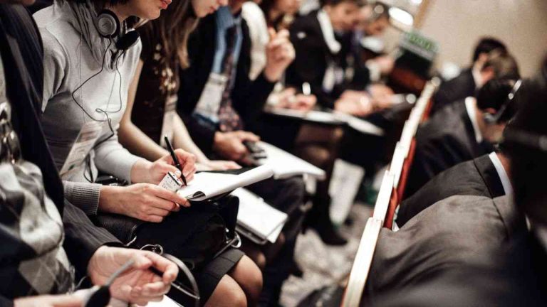 People sit in a row and write about what the media’s image of disasters shows.