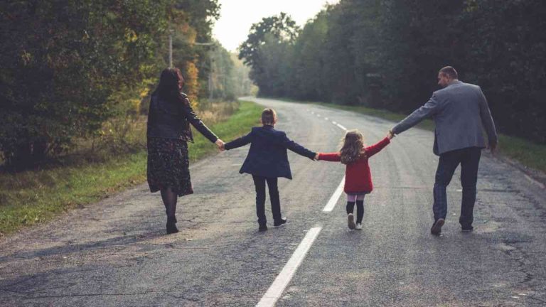 A man and a woman walking down a road with their son and daughter, illustrating differences in upbringing.
