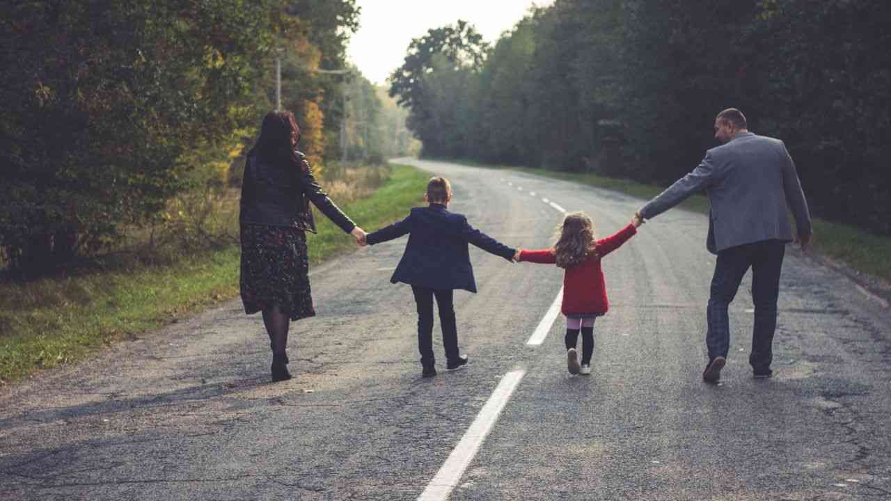 A man and a woman walking down a road with their son and daughter, illustrating differences in upbringing.