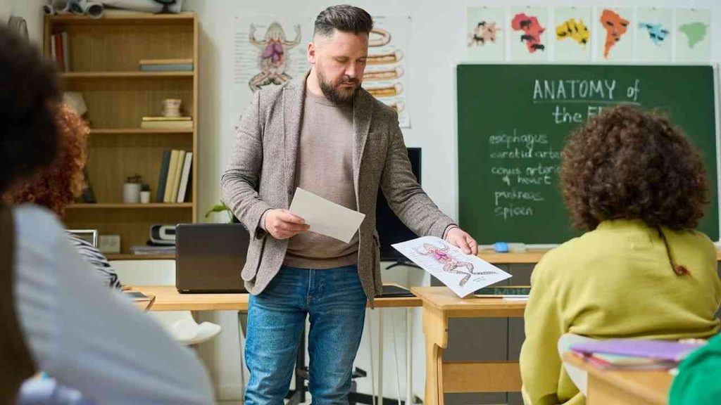 A teacher hands out materials to students, offering a clue to how to recognise a good school.