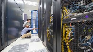 Two men in a narrow corridor working on databases.