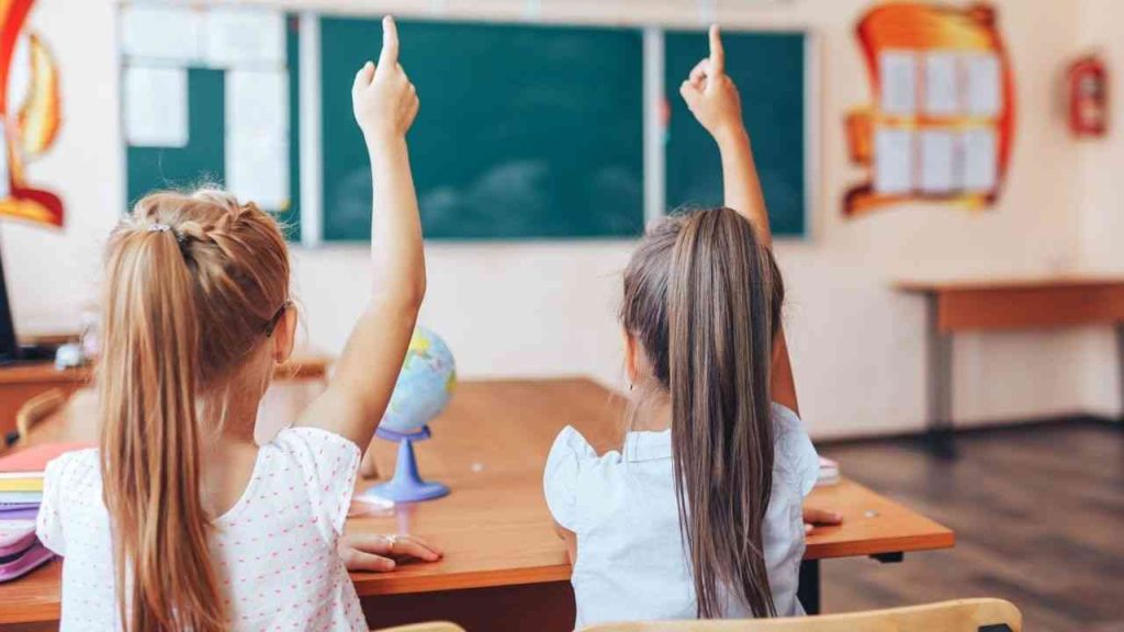 Two girls raise their hands to answer.