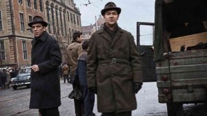 SB secret police officers. Men standing on a street in communist-era Poland, beside a car and urban buildings.
