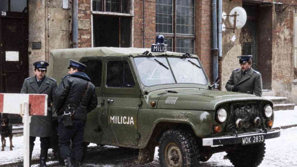 Citizens’ Militia officers beside a police car in communist-era Poland.