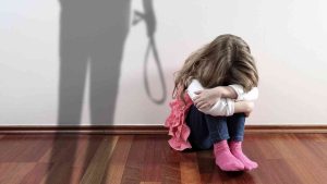 A child sitting huddled against a wall, with the shadow of an adult holding a belt cast on it—a symbol of violence against children.