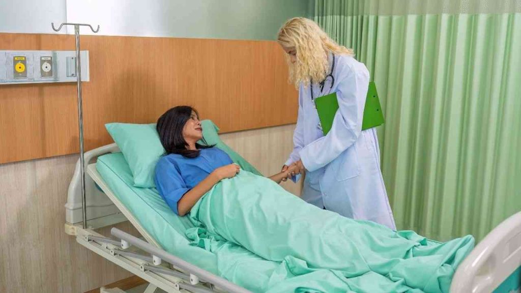 
A female doctor leans over a female patient lying in a hospital bed, illustrating healthcare spending.