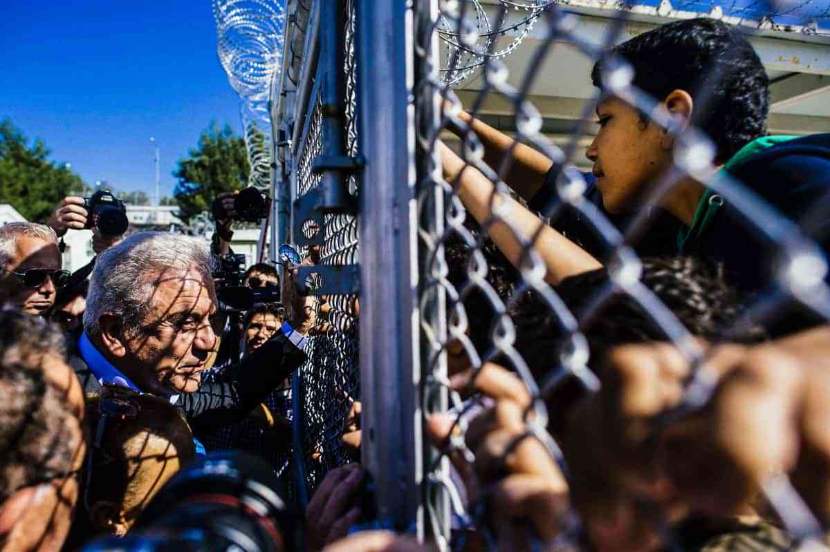 TOPSHOTS European Migration Commissioner Dimitris Avramopoulos (L) talks to migrant children through a metal fence at the 