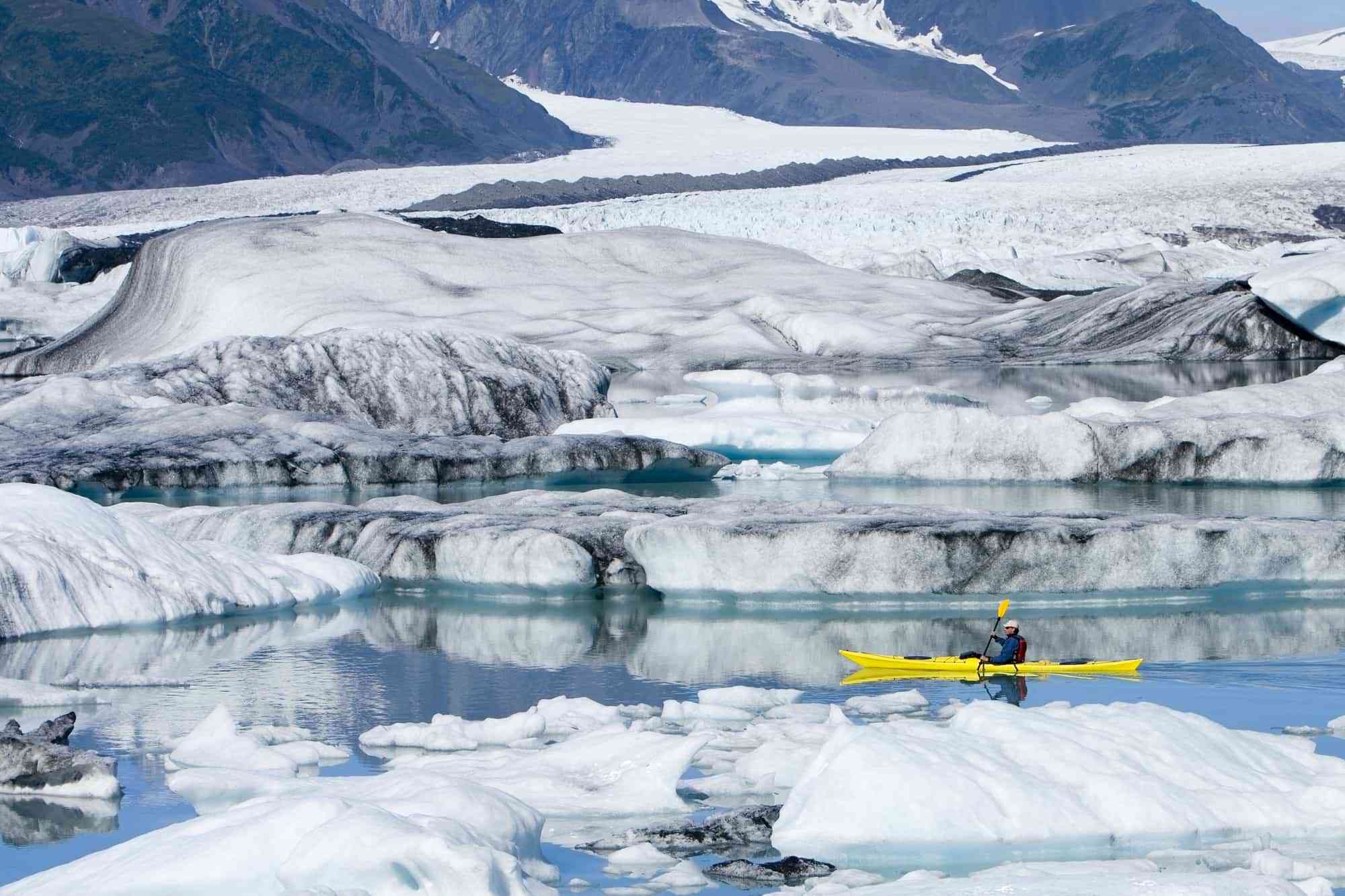 Female kayaker paddles yellow kayak in Bear Cove Lagoon Resurrection Bay Alaska Kenai Fjords NP Kenai Peninsula summer