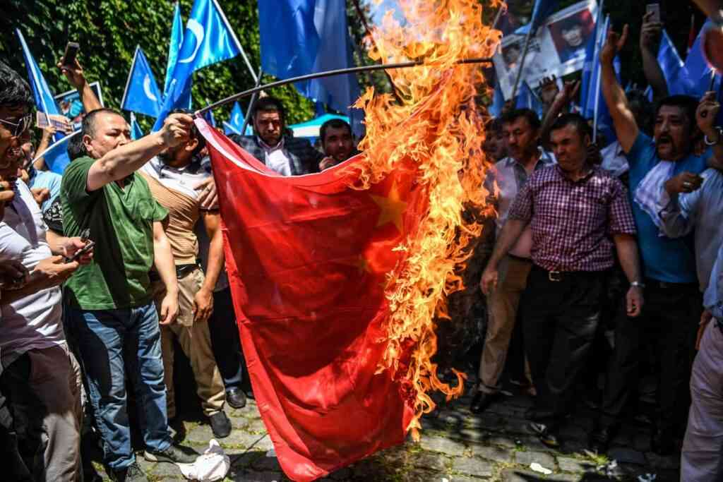 Supporters of the mostly Muslim Uighur minority and Turkish nationalists burn a Chinese flag during a protest to denounce China's treatment of ethnic Uighur Muslims during a deadly riot on July 2009 in Urumqi, in front of the Chinese consulate in Istanbul, on July 5, 2018. Nearly 200 people died during a series of violent riots that broke out on July 5, 2009 over several days in Urumqi, the capital city of the Xinjiang Uyghur Autonomous Region, in northwestern China, between Uyghurs and Han people.   / AFP PHOTO / OZAN KOSE