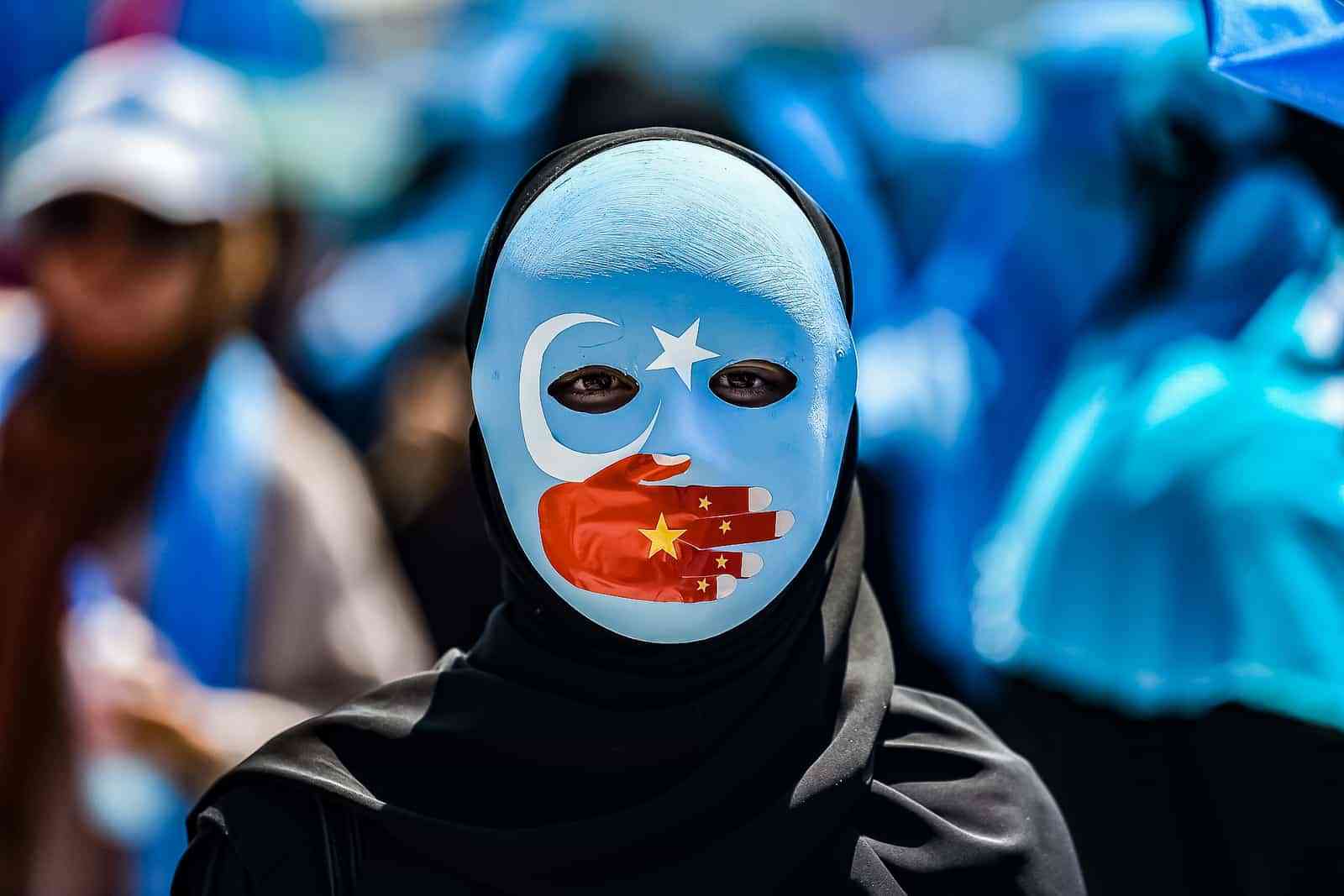 TOPSHOT - A demonstrator wearing a mask painted with the colours of the flag of East Turkestan and a hand bearing the colours of the Chinese flag attends a protest of supporters of the mostly Muslim Uighur minority and Turkish nationalists to denounce China's treatment of ethnic Uighur Muslims during a deadly riot in July 2009 in Urumqi