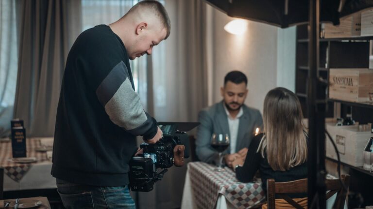 Prawda i fikcja w reality shows: kamerzysta nagrywa mężczyznę i kobietę przy stoliku w restauracji