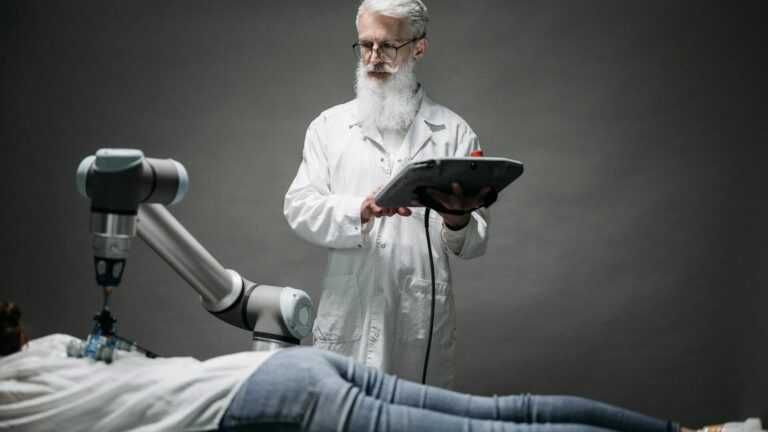 roboty chirurgiczne w Polsce, naukowiec patrzacy na robotyczne ramie, które masujue leżącą kobietę.