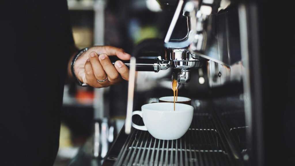 wpływa kawy na zdrowie, barista szykujący filiżanke kawy. 