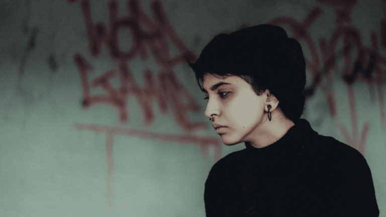 Uzależniające substancje: przygnębiona i zamyślona dziewczyna na tle ściany z graffiti