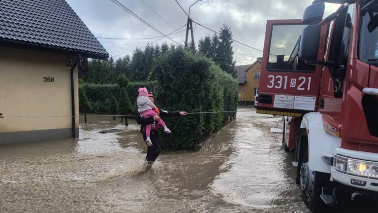 Kolejna powódź: strażak przenosi nad wodą dziecko