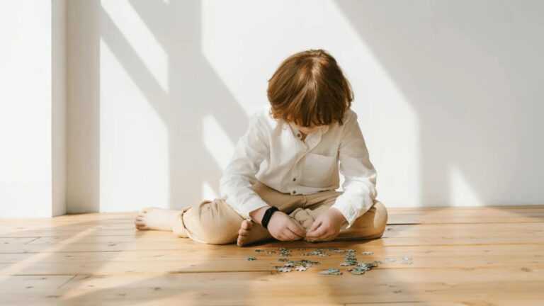 leczenie autyzmu: dziecko układające puzzle na podłodze.