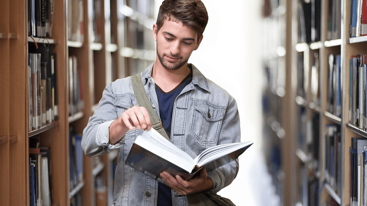 proces uczenia się: student w bibliotece przegląda książkę.