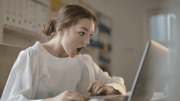 Sposób na hejt: kobieta w szoku, z otwartymi ustami wpatruje się w ekran laptopa