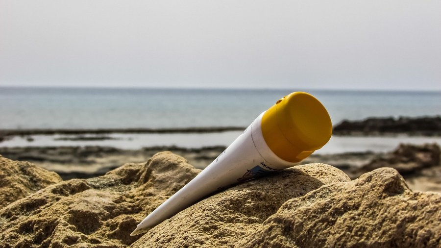 Oparzenia słoneczne, krem do opalania leży w piasku na plaży