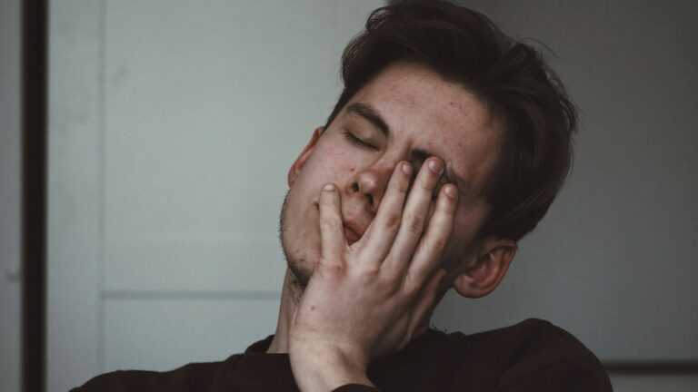 Zaburzenia depresyjne: mężczyzna zakrywa częściowo twarz ręką