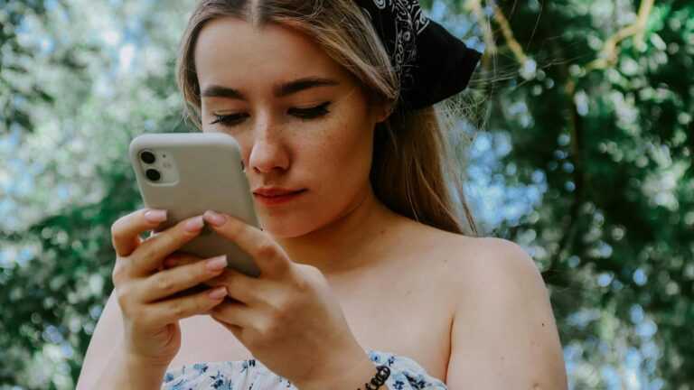 Przyszłość social mediów: skupiona kobieta w chuście na głowie patrzy na ekran smartfona