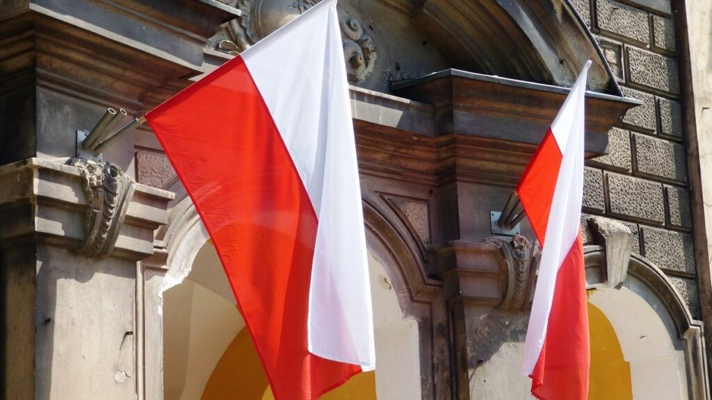 Rozwój Polski. Biało-czerwone flagi wiszące z okien. Fot. Tomasz_Mikolajczyk/Pixabay