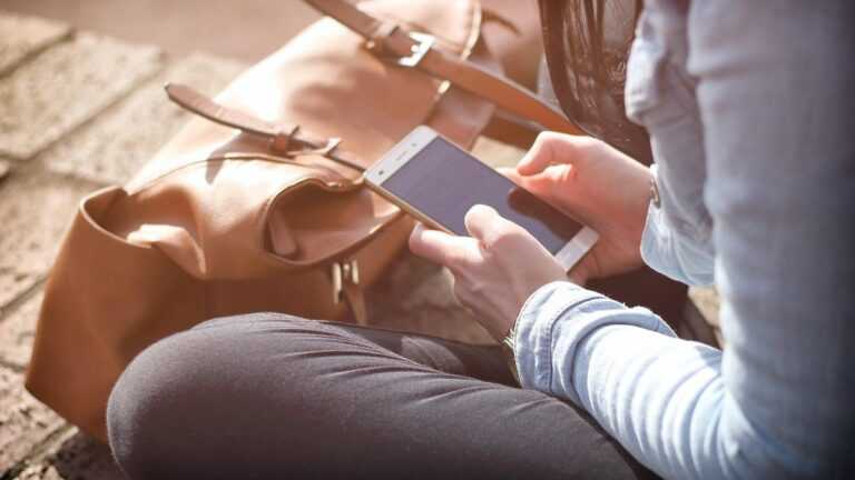 Wpływ języka na relacje, kobieta trzyma smartfona w ręku