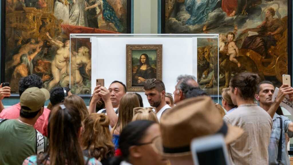 Odbiór dzieła sztuki: tłum oglądających przed gablotą z Mona Lisą