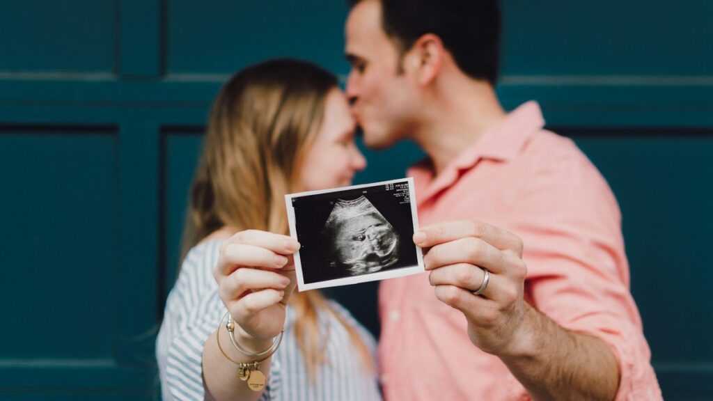 Pokolenie Z i aborcja: mężczyzna całuje kobietę w czoło, trzymają razem zdjęcie z USG ciąży