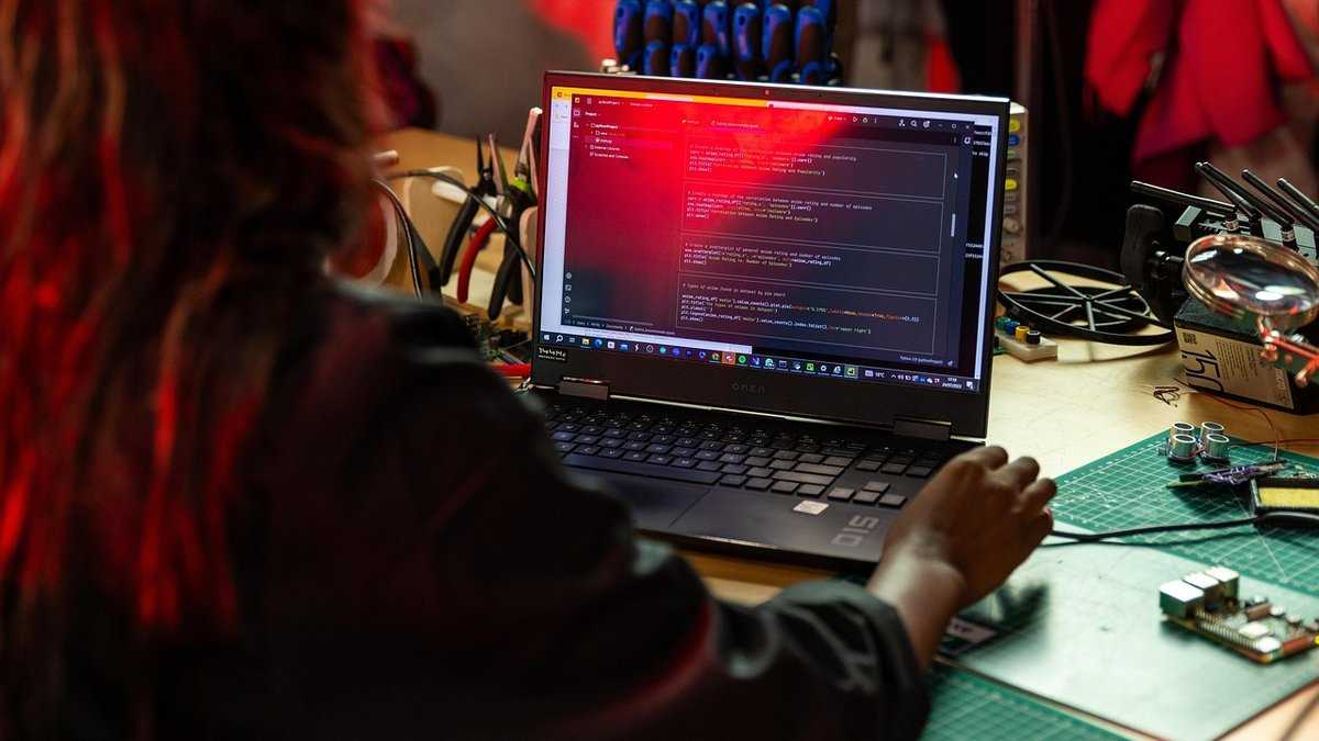 ai do oszustw, Fot. This_is_Engineering/pixabay. Osoba pracuje przy laptopie z wyświetlonym kodem w ciemnym, technologicznym otoczeniu.