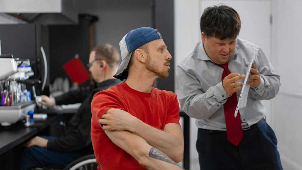 Dorosłość z zespołem Downa: pracownik z zespołem Downa rozmawia z innym pracownikiem w biurze