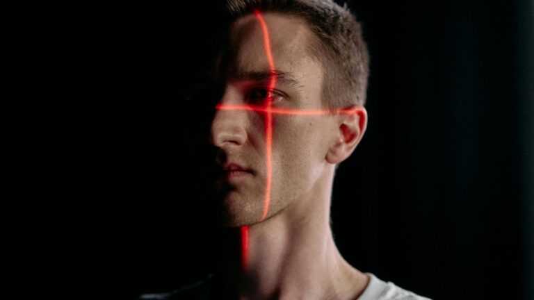 hologram nowej generacji, Fot. cottonbro studio/pexels, Twarz mężczyzny oświetlona czerwonymi liniami lasera w ciemności