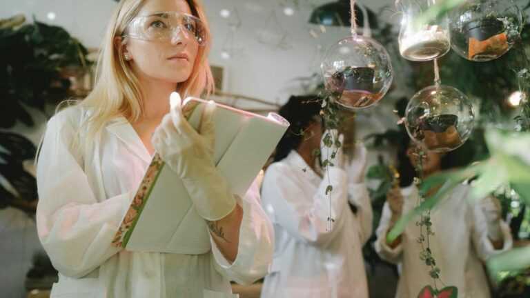 zagrożone gatunki na Ziemi, Fot. Yaroslav Shuraev/pexels, Badaczka obserwuje rośliny w laboratorium biologicznym.