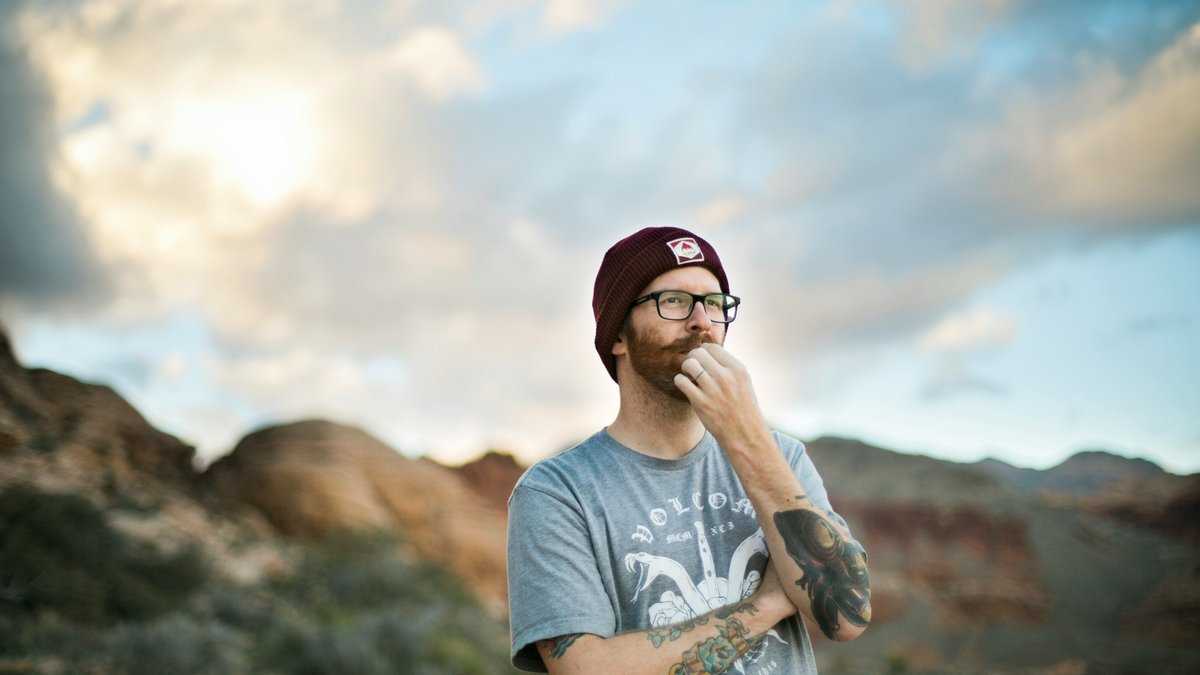 inteligencja a geny. Mężczyzna w czapce i okularach stoi zamyślony na tle górskiego krajobrazu. Fot. Kitera Dent/Unsplash