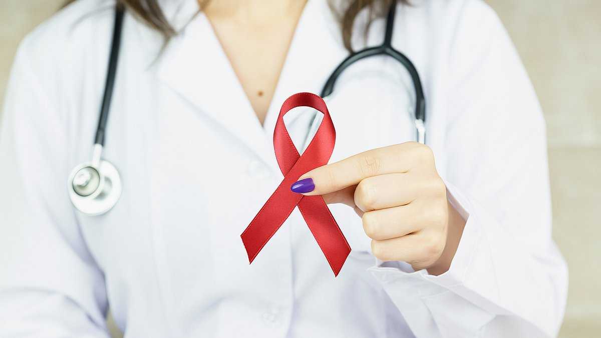 Leczenie wirusa HIV: Kobieta w białym fartuchu medycznym trzyma czerwoną wstążkę – symbol walki z HIV. Fot. Bermix Studio/unsplash