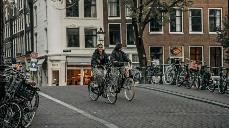Miasta bez samochodów: dwie kobiety jadą na rowerach w Amsterdamie