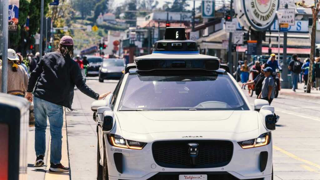 Miasta bez samochodów: mężczyzna obok autonomicznej taksówki w San Francisco