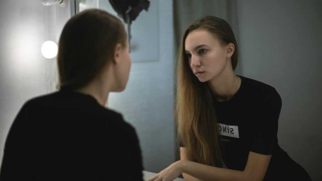 Syndrom oszusta: zamyślona kobieta patrzy w lustro