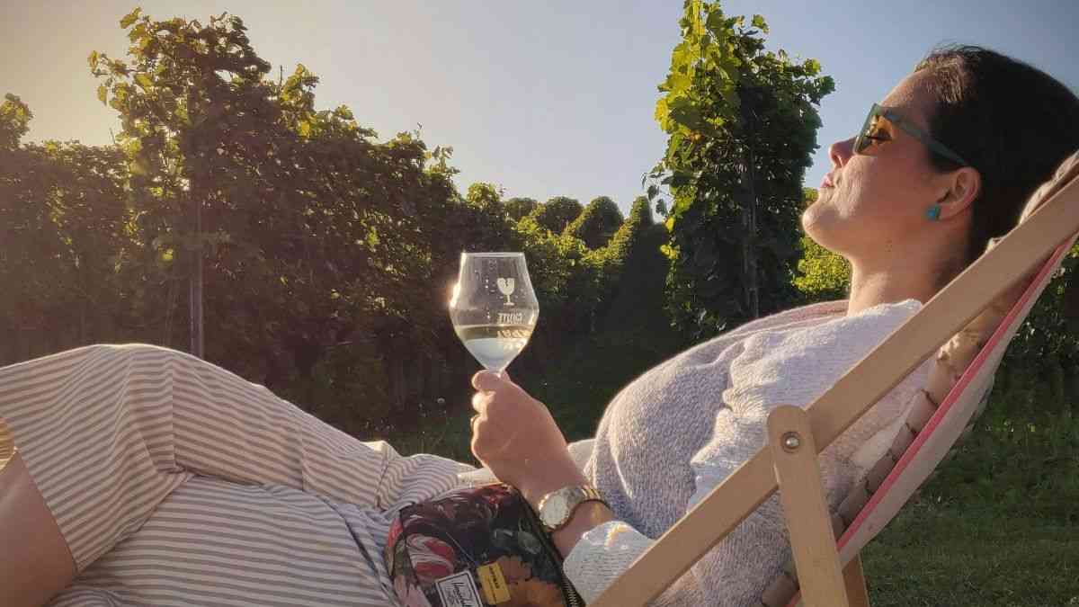 Czy alkohol relaksuje: kobieta w ogrodzie na leżaku pije wino z kieliszka. Fot. Manuel Campagnoli / Unsplash
