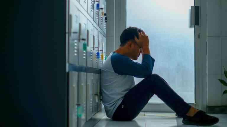 Jak leczyć PTSD: załaman mężczyzna z głową w dłoniach siedzi przy rzędzie szafek. Fot. Yosi Prihantoro / Unsplash