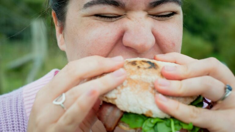 Gen otyłości badania: kobieta ze smakiem je kanapkę. Fot. Harry Grout / Unsplash