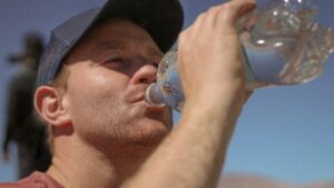 Mężczyzna pije wodę z plastikowej butelki – mikroplastik w napojach i żywności